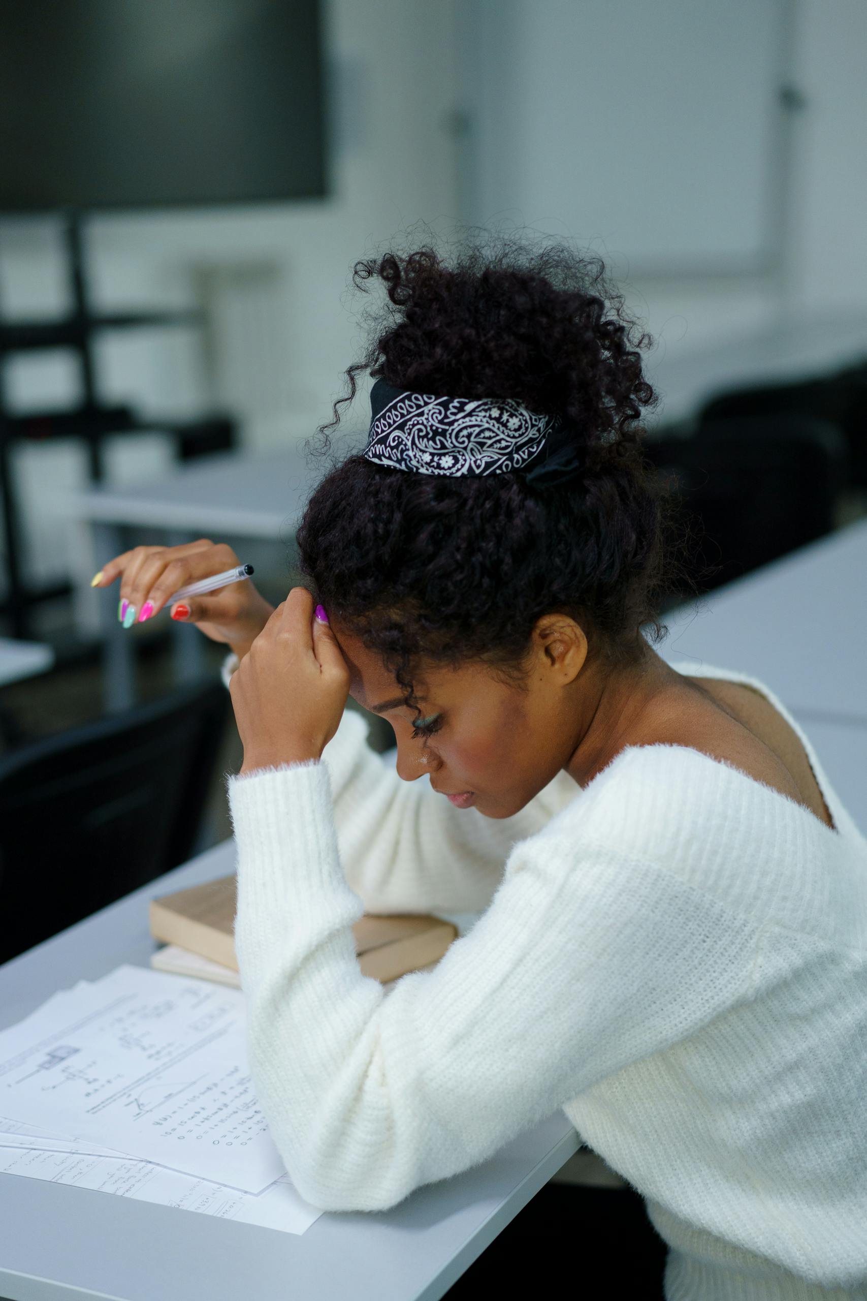 A young woman deeply concentrating while sitting at a desk with study materials.